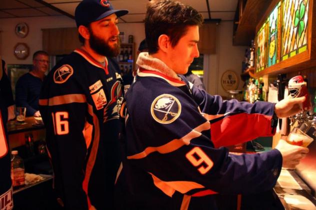 Allan McPherson pours a beer as Zach Cohen looks on