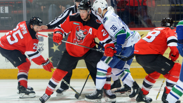 Binghamton Devils Center Kevin Rooney holds off the Utica Comets