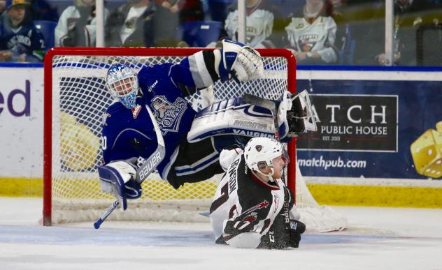 Victoria Royals Goaltender Griffen Outhouse is upended by Tyler Benson of the Vancouver Giants