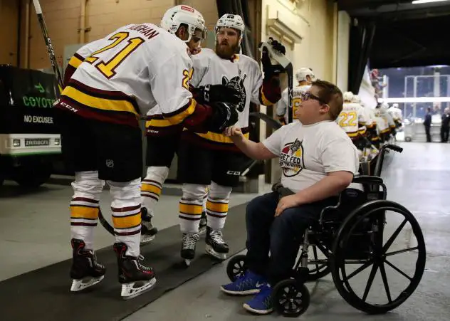 Scooter Vaughan of the Chicago Wolves greets young fan Blake Burriss