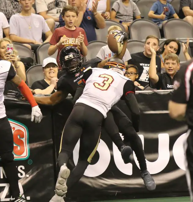 An Arizona Rattlers receiver is tackled into the boards by a member of the Iowa Barnstormers
