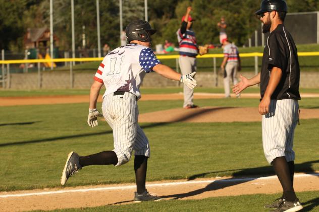 Blake Baumgartner extends a hi-five to Medford Rogues' third base coach Mike Takamori