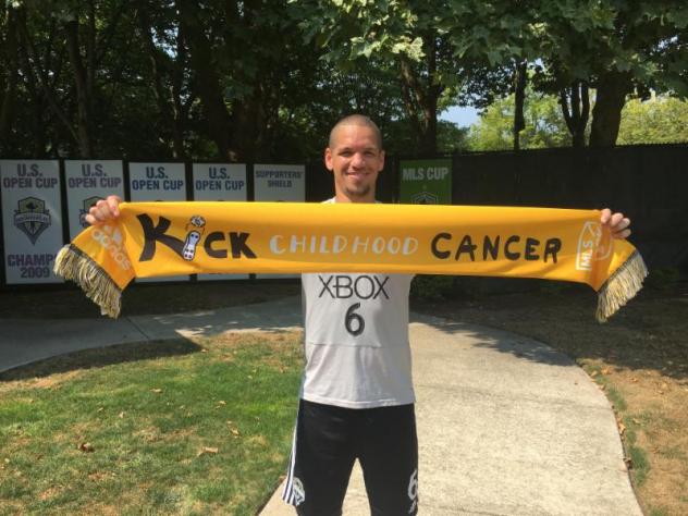 Seattle Sounders captain Ozzie Alonso poses with a Kick Childhood Cancer scarf
