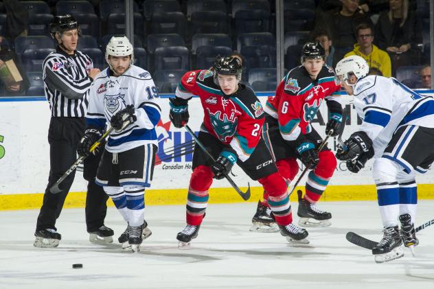 Kelowna Rockets centre Kyle Topping (center) eyes a loose puck against the Victoria Royals