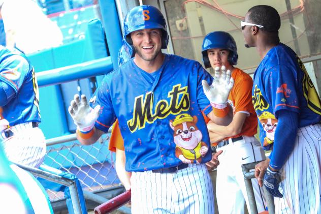 Tim Tebow reacts in the Syracuse Mets dugout to getting the silent treatment from his teammates after hitting his first career Triple-A home run