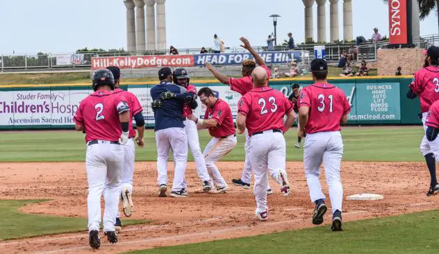 The Pensacola Blue Wahoos mob Jaylin Davis at first base after his game-winning hit