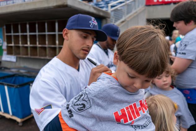 Mark Contreras of the Pensacola Blue Wahoos signs the shirt of a young fan