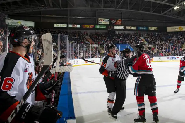 An official steps in between Mark Liwiski of the Kelowna Rockets and the Medicine Hat Tigers