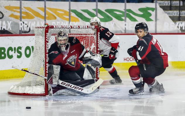 Vancouver Giants goaltender Trent Miner and defenceman Alex Kannok Leipert eye the puck vs. the Prince George Cougars
