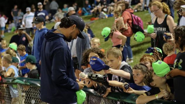 Kane County Cougars pitcher Christian DeLeon signs autographs for fans in the lawn area