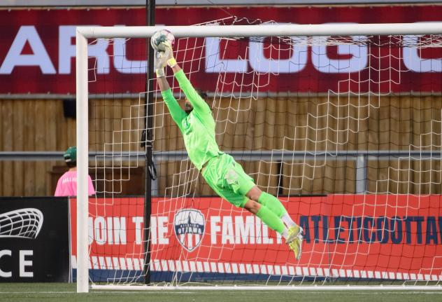 Atlético Ottawa goalkeeper Nathan Ingham stretches to make a save