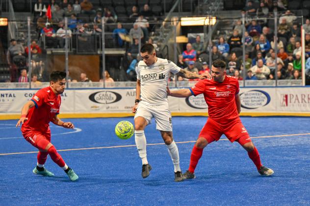 Florida Tropics defender Lucas Montalres dribbles between two Kansas City Comets