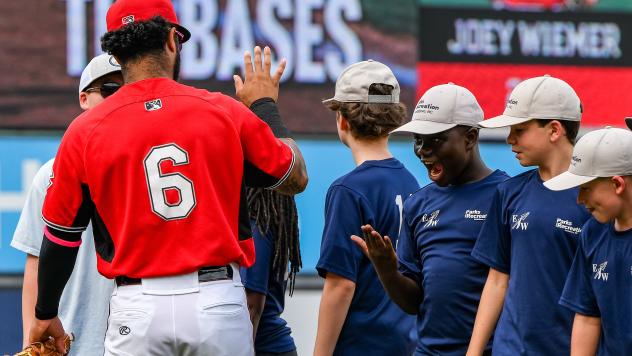 Hedbert Perez of the Carolina Mudcats gives high fives to young fans