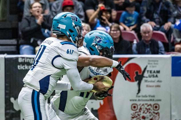 Massachusetts Pirates quarterback Kenji Bahar hands off