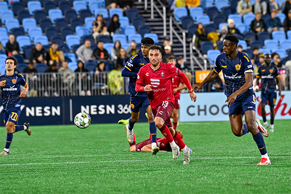Louis Perez of North Carolina FC (center) eyes a loose ball