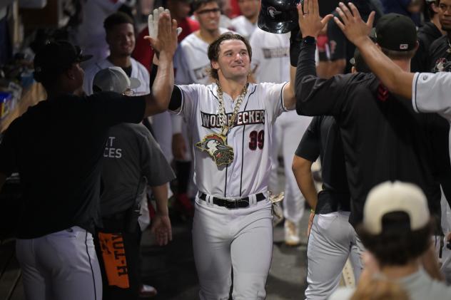 Cam Fisher receives high fives from the Fayetteville Woodpeckers in the dugout