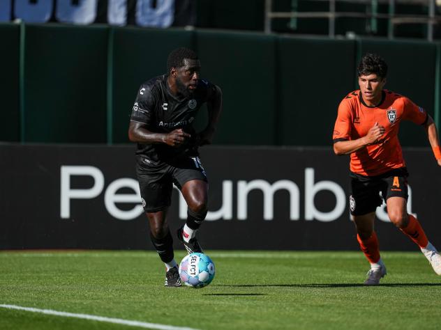 Oakland Roots' Neveal Hackshaw and Orange County SC's Nico Benalcázar in action
