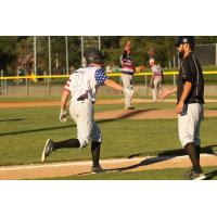 Blake Baumgartner extends a hi-five to Medford Rogues' third base coach Mike Takamori